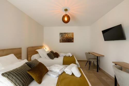 two beds in a room with a tv and a desk at Domaine le St Georges - Piscine in Saint-Sauveur-le-Vicomte