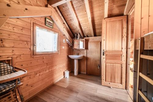 a bathroom in a log cabin with a sink and a door at Chalet 6p Premium - La Bergeronette in Verchaix