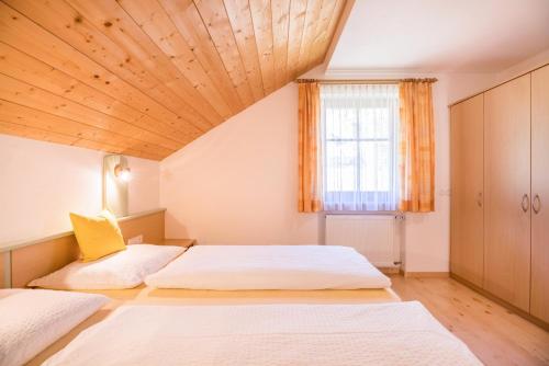 two beds in a bedroom with a wooden ceiling at Kuglerhof Apt 1 in Cadipietra
