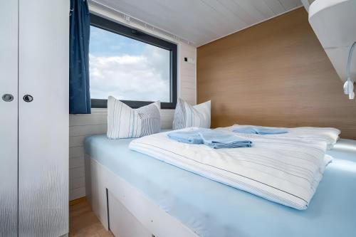 a large white bed in a room with a window at Entspannung pur - Hausboot Liberty in Fürstenberg