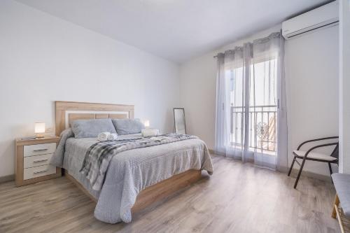 a white bedroom with a bed and a window at Bright Apartment In Maracena in Granada