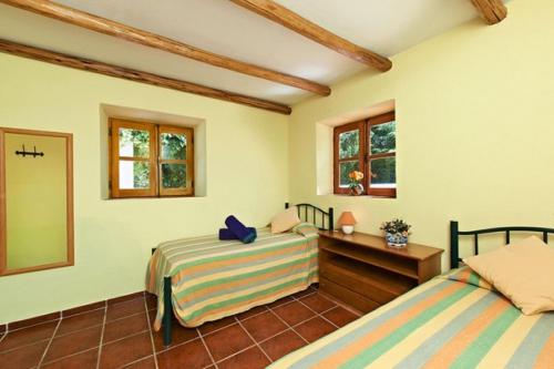 a bedroom with two beds and a desk and windows at Quinta da Aroeira in Lagoa