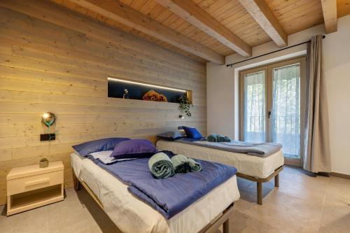 two beds in a room with wooden walls at Casa Meg in Tremosine Sul Garda