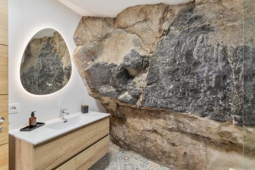 a bathroom with a rock wall and a sink at Casas de Vacaciones Ibaiale in Cazadores