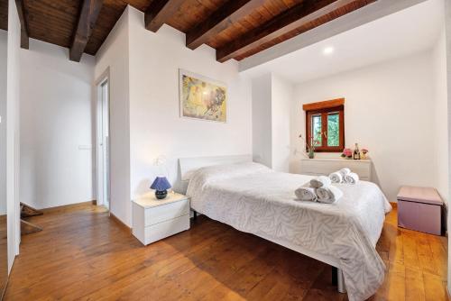 a bedroom with a white bed and a wooden floor at La Sosta di Isa in Delebio