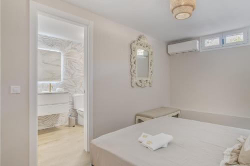 a white bedroom with a bed and a bathroom at Las Mimosas Ronda in Ronda