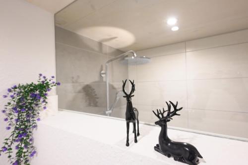 two statues of deer sitting on a counter in a bathroom at Ferienwohnung Talblick in Kappelrodeck