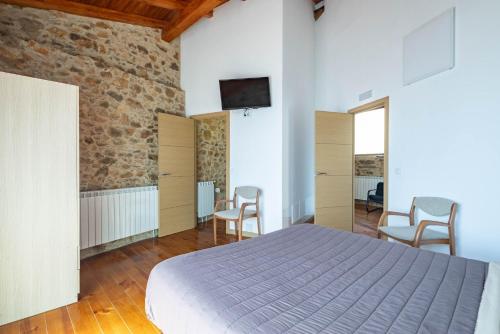 a bedroom with a bed and two chairs and a tv at Casa Silverio in Monforte de Lemos