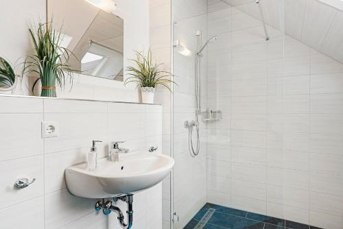 a white bathroom with a sink and a shower at Deluxe Ferienwohnungen Diana in Radolfzell am Bodensee