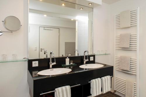 a bathroom with two sinks and a large mirror at Ferienhaus Jümmers - Hein Mück in Horumersiel