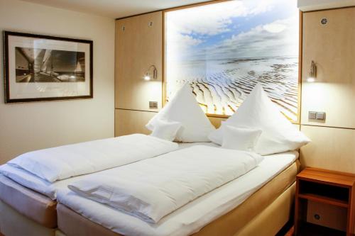 a bed in a room with a picture on the wall at Ferienhaus Jümmers - Hein Mück in Horumersiel
