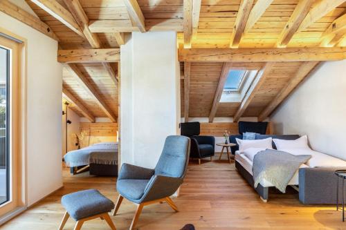 a room with two beds and chairs and wooden ceilings at Alpview Loft Garmisch in Garmisch-Partenkirchen