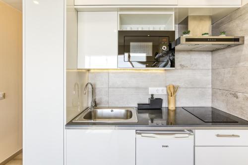 a kitchen with white cabinets and a sink at Atic Moon Miami in Empuriabrava