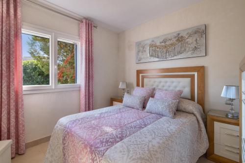 a bedroom with a bed and two windows at Duplex Islantilla Golf in Huelva