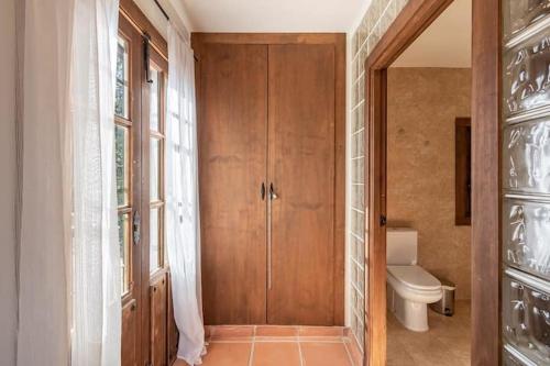 a bathroom with a toilet and a wooden door at La Casa 1950 in Montefrío