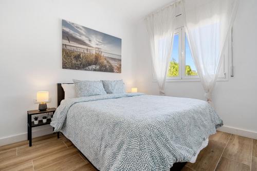 a white bedroom with a bed and a window at The Sunset Calafell in Calafell
