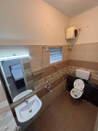 a bathroom with a sink and a toilet and a mirror at Silver Breeze in Yercaud