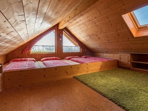 a bed in a wooden room with two windows at Ferienwohnung Heimatgefühl Thalheim in Leibertingen