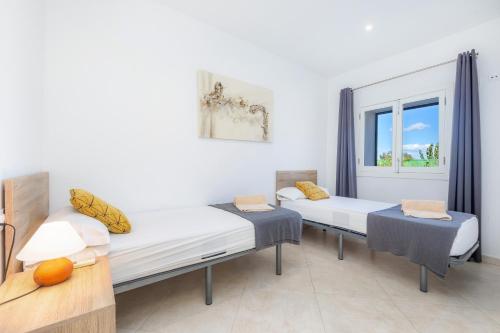 two beds in a room with a window at Ca Na Bergues in Ariany