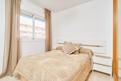 a white bedroom with a bed and a window at Marina De El Morche in Torrox
