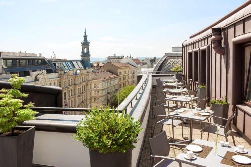 a balcony with tables and chairs and a view of the city at NH Collection Wien Zentrum in Vienna