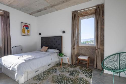 a bedroom with a bed and a window and a chair at Casa Cándido in Ribarteme