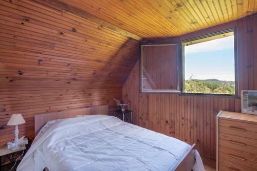 a bedroom with a bed in a wooden room with a window at Gite Anje in Peyrouse
