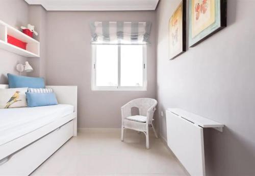 a white bedroom with a white bed and a chair at Denia Living in Denia