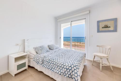 a bedroom with a bed and a chair and a window at Casa Miramar in Sa Ràpita