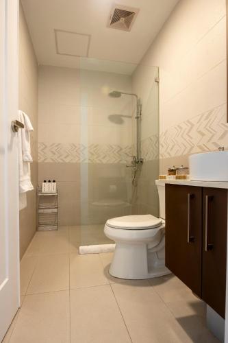 a bathroom with a toilet and a glass shower at Stylish Condo with Rooftop Pool and Gym in Kingston
