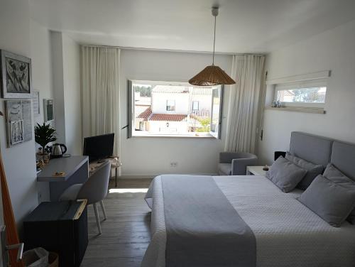 a bedroom with a bed and a desk and a window at Silver Home in Nazaré