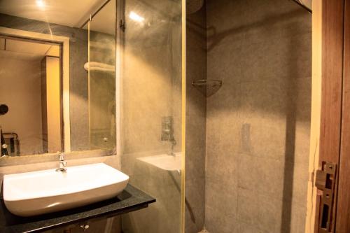 a bathroom with a sink and a glass shower at Banyan Palace in Chennai