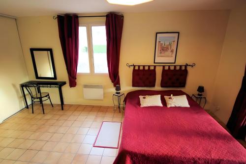 a bedroom with a red bed and a window at Gite La Roseraie in Ruoms