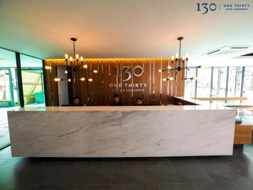 a lobby with a reception counter with people in the background at 130 Hotel & Residence Bangkok in Bangkok