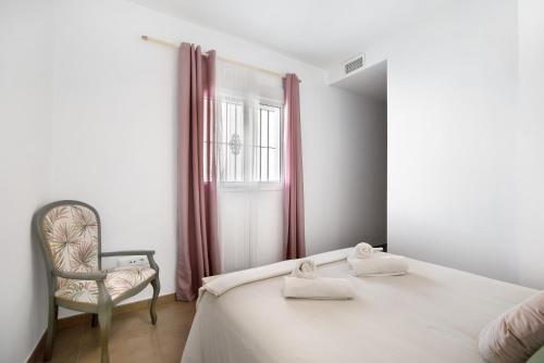 a bedroom with a bed and a chair and a window at Piso arquillo del reloj in Chiclana de la Frontera