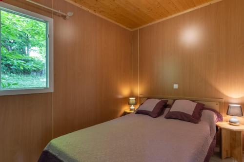 a bedroom with a bed and a window at Maisons Cozy - Mas Lachamp in Gravières