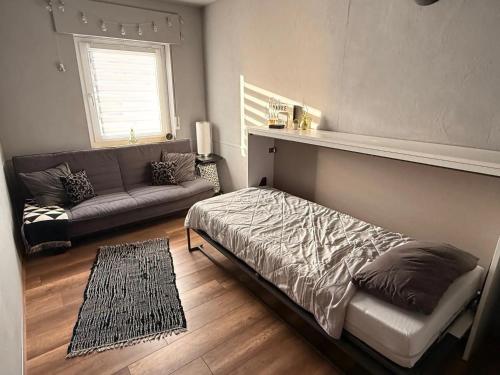 a bedroom with a bed and a couch and a window at Ferienwohnung Seus in Dorfprozelten