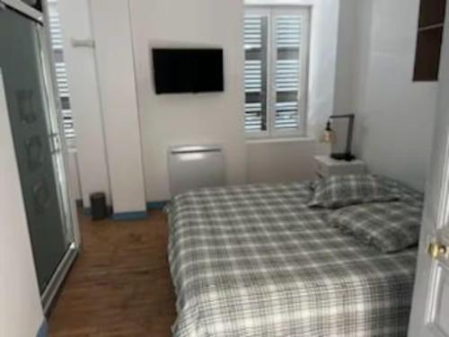 a bedroom with a bed and a tv on the wall at Appartement T 2 in La Bourboule