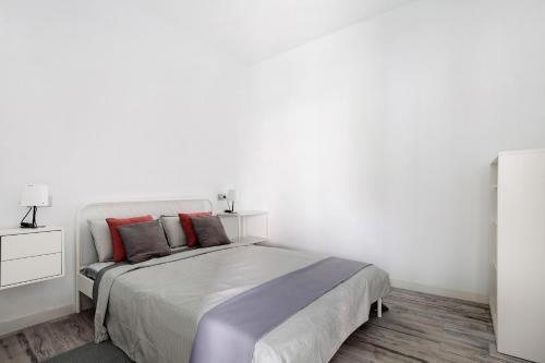 a white bedroom with a large bed with red pillows at La Corte A2 in Antigua