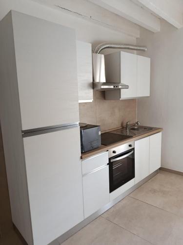 a kitchen with white cabinets and a refrigerator at Via Roma 50 in Bacu Abis
