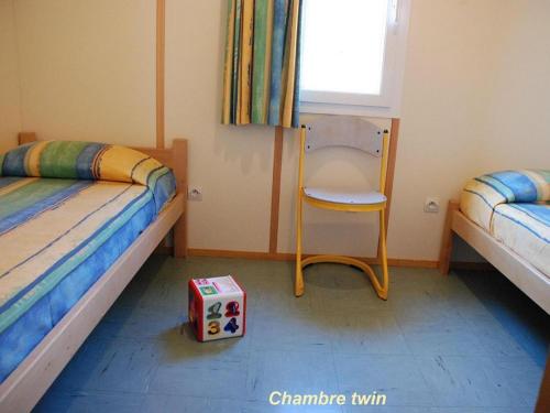 a bedroom with two beds and a chair and a box at 5 Chalet Iris in Blavignac