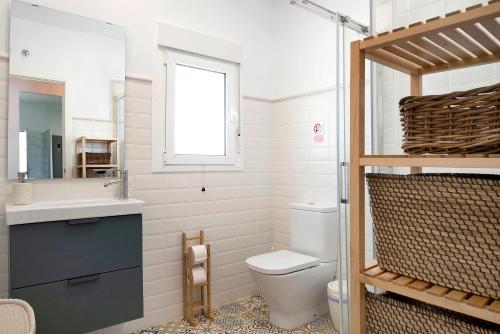 a bathroom with a toilet and a sink and a mirror at La Casita de la Florida in Conil de la Frontera