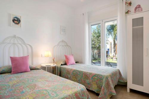 a bedroom with two beds with pink pillows at La Casita de la Florida in Conil de la Frontera