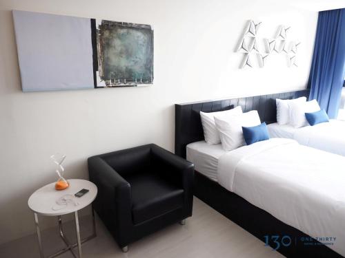 a hotel room with two beds and a chair at 130 Hotel & Residence Bangkok in Bangkok