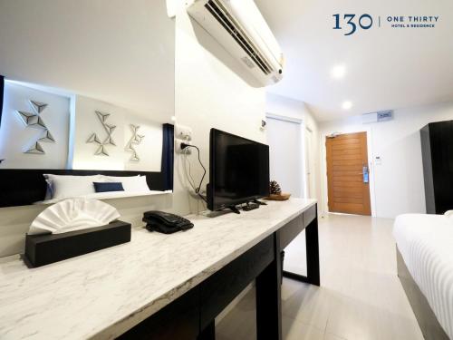 a room with a bed and a television on a counter at 130 Hotel & Residence Bangkok in Bangkok
