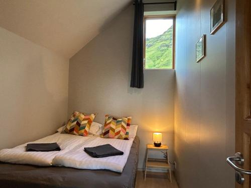 a small bedroom with a bed with a window at Mountain View Apartment at Rauðafell in Hvolsvöllur