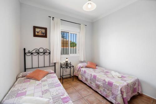 two beds in a room with a window at Chalet Isla del Sotillo in Chiclana de la Frontera