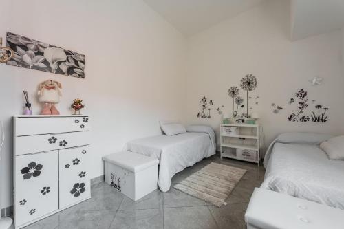 a white bedroom with two beds and a dresser and a dresser at Red House Capoterra in Capoterra