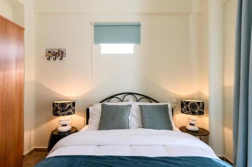 a bedroom with a white bed with two lamps at Seaside House In Agios Vasilios in Patra