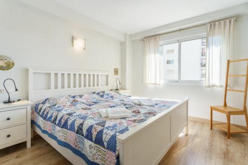 a white bedroom with a bed and a chair at Apartment Acapulco in Fuengirola